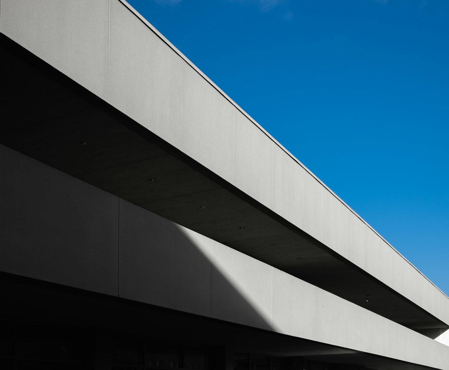 Facciata di un edificio moderno con linee orizzontali nette su sfondo blu.